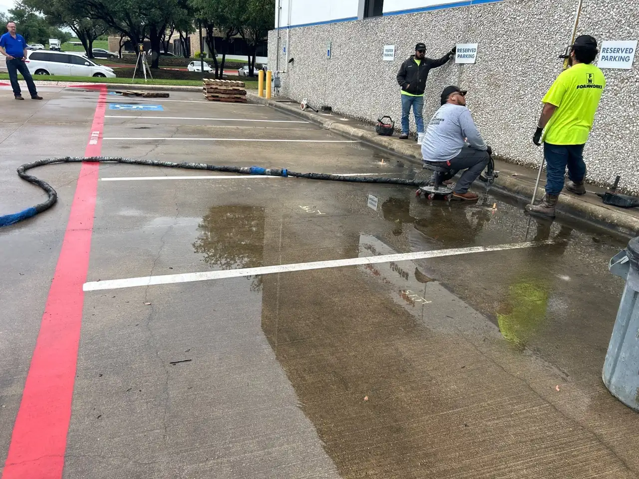 Crew lifting settled concrete in a commercial parking lot