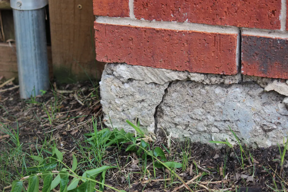 Cracked brick foundation corner on a Fort Worth home in need of repair