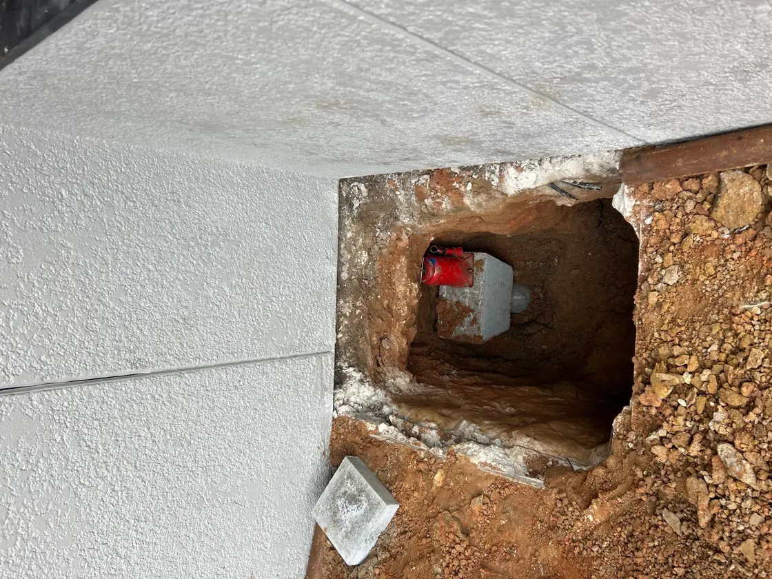 Hydraulic ram set in a pier hole cut at a slab edge