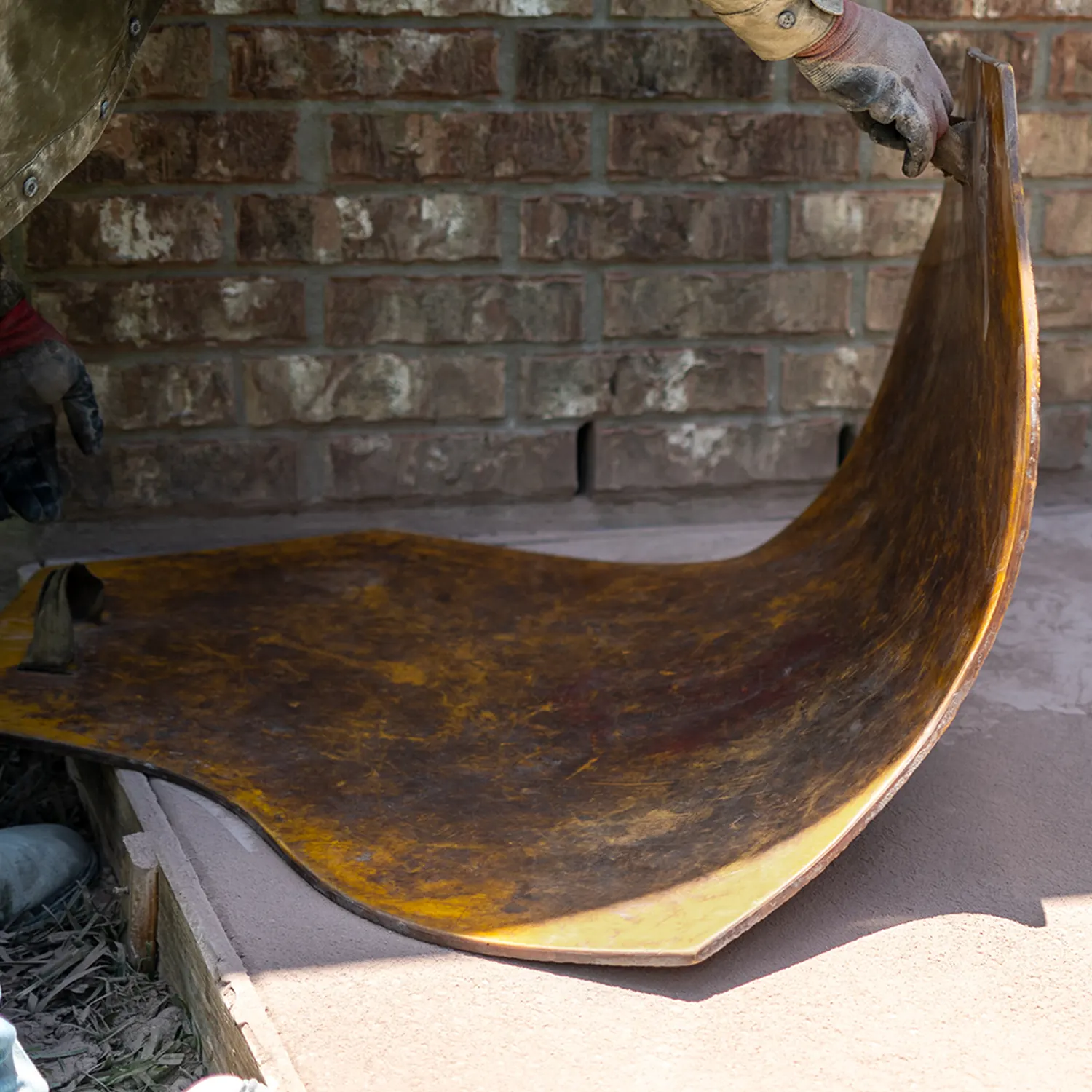 Stamping mat being applied to fresh concrete during a stamped concrete installation