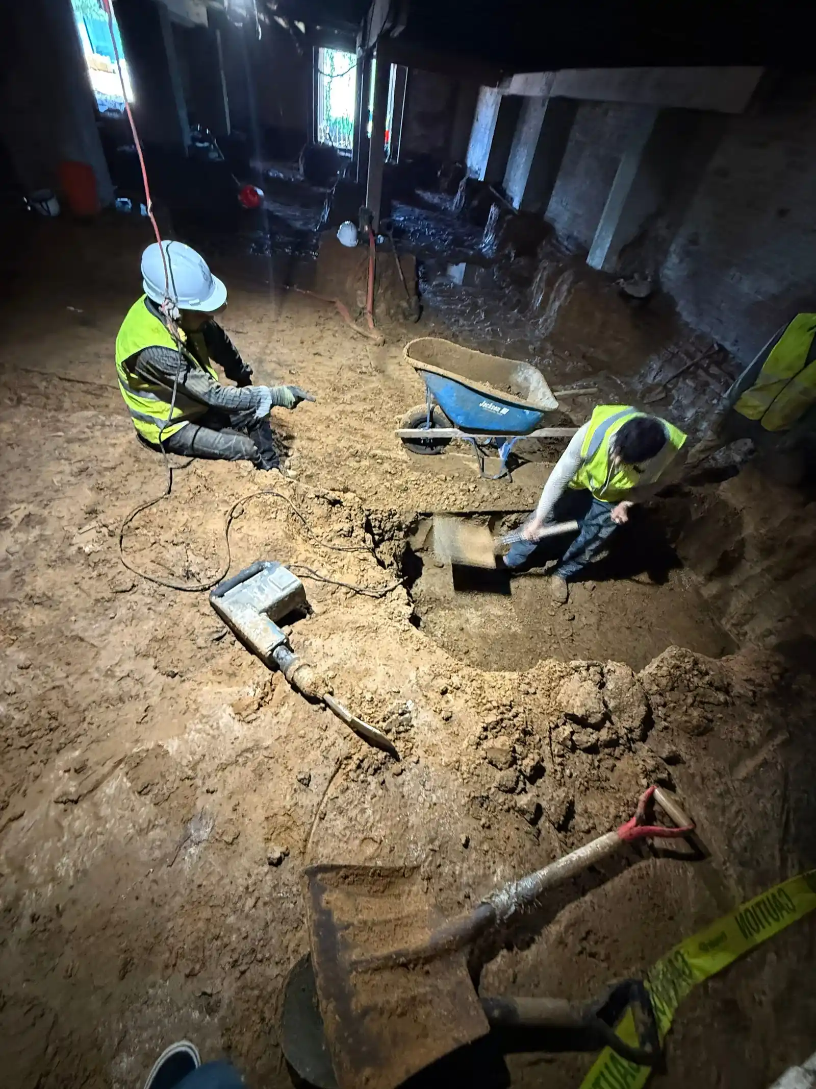 Crew performing underpinning work beneath an existing structure